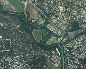 Vue aérienne du cours d'eau, de sa sinuosité et de sa ripisylve, en milieu urbain.